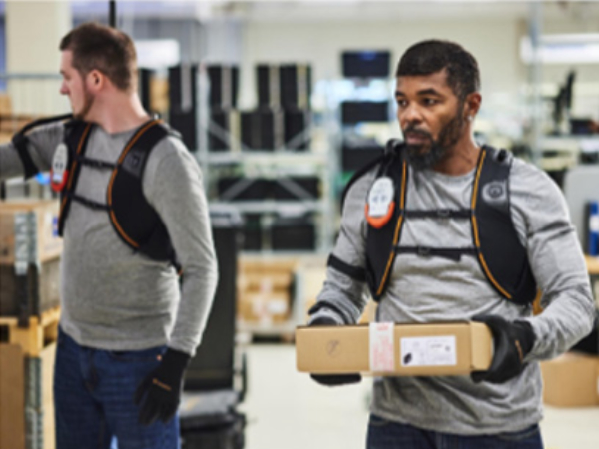 Men wearing exoskeleton shoulder protection at a logistics hub.